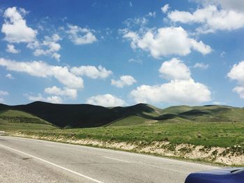 Road amidst field against sky