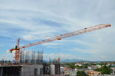 Cranes at construction site against sky in city