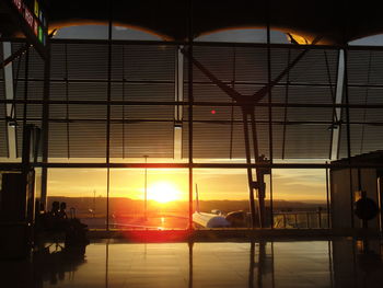 Silhouette man in illuminated building against sky during sunset