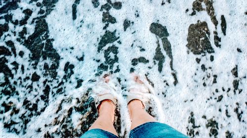 Low section of woman standing on shore at beach