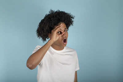 Young  peeking out in shock covering face and eyes with hand, looking through fingers 