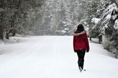 Rear view of young woman walking on snowfield