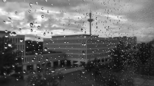 Full frame shot of wet glass window against cloudy sky