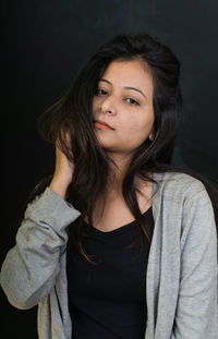 Close-up portrait of beautiful young woman over black background