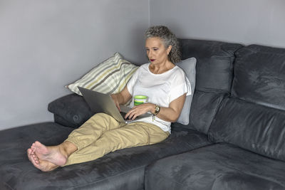 Young man using mobile phone while sitting on sofa at home