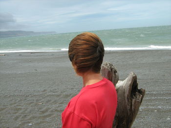 Person standing on sand at beach against sky