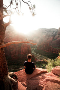 Rear view of woman sitting on mountain