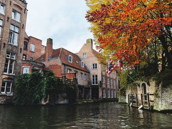 River amidst buildings against sky during autumn