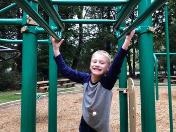 Portrait of happy boy standing amidst jungle gym in playground