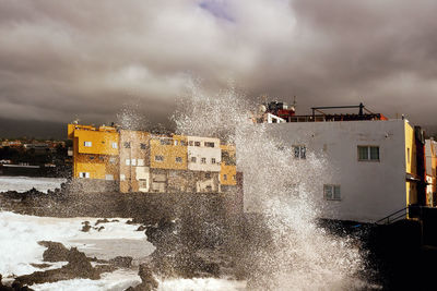 Water splashing in sea against cloudy sky