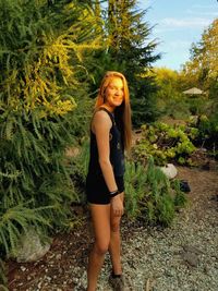 Portrait of smiling young woman standing against plants