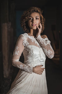 Portrait of beautiful woman in wedding dress standing at home