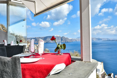 Chairs and tables in restaurant by sea against sky