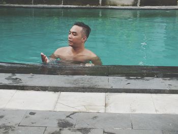 Shirtless man swimming in pool