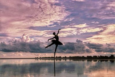 Silhouette man surfing on lake against sky during sunset