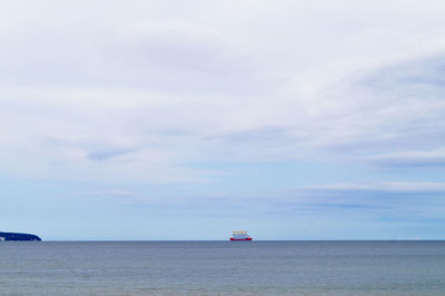 Distant view of ship against cloudy sky