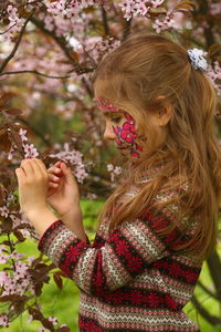 Spring portrait of a six year old girl standing under the blooming pink cherry tree