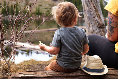 Small boy and mother sitting near lake