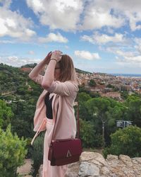 Rear view of woman looking at cityscape against sky