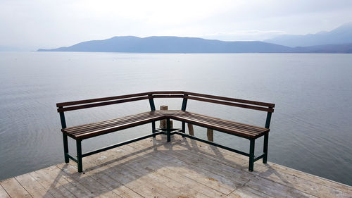 Chair on table by sea against sky