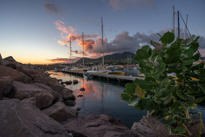 Sailboats moored on lake against sky during sunset