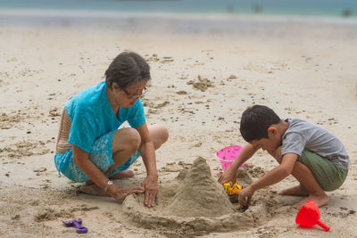 Granddaughter and son making sandcastle at beach