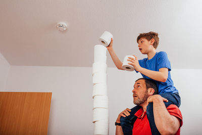 Full length of father and son against wall at home