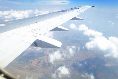 Aerial view of airplane wing over clouds