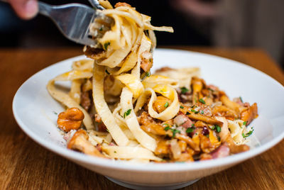 Close-up of person eating spaghetti with fork