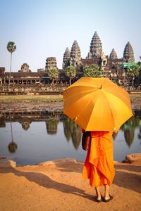 Rear view of woman walking in temple against clear sky