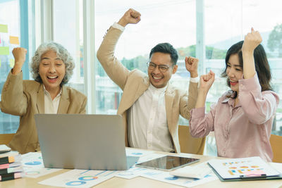 Group of asian team business people hand raise up with happiness in meeting room office.