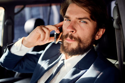 Portrait of businessman using mobile phone in car