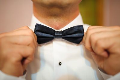 Midsection of man adjusting tied bow