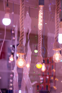 Low angle view of illuminated light bulb hanging at night