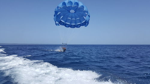 Scenic view of parasailing against clear blue sky