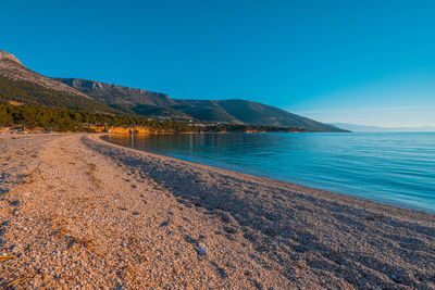 Scenic view of beach against clear blue sky