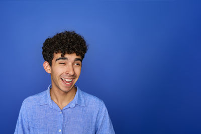 Portrait of young man standing against blue background