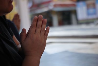 Midsection of woman with hands clasped outdoors