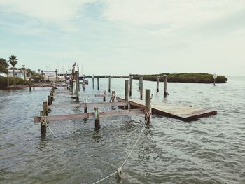 Wooden posts in sea against sky