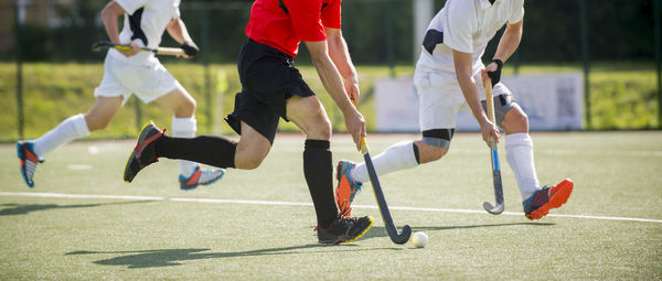 Low section of men playing hockey on turf