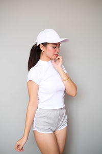 Young woman wearing hat standing against white background