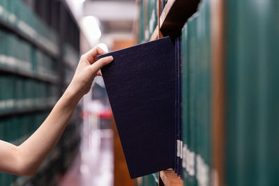 Close-up of hand removing book from shelf in library