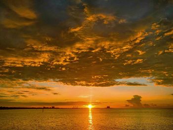 Scenic view of sea against dramatic sky during sunset