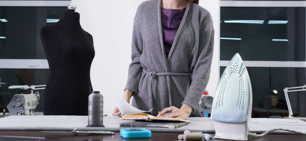 Midsection of fashion design standing by table