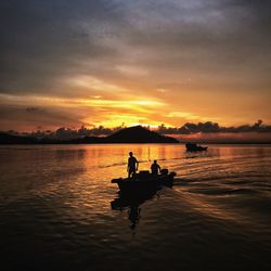 Silhouette boat in lake against sky during sunset