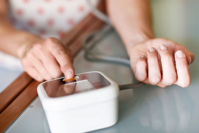 Midsection of woman holding smart phone on table