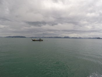 Boats in sea against cloudy sky