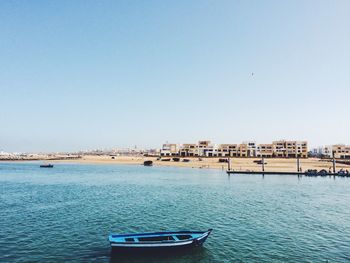 Boats in calm sea against clear sky