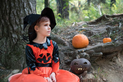 Boy looking away while sitting on tree