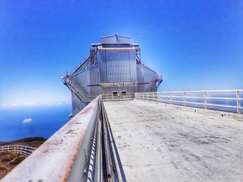 Built structure by sea against clear blue sky